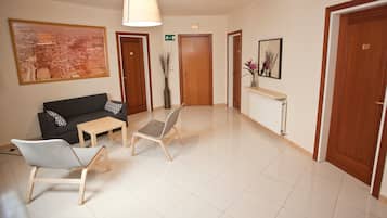 Un vestíbulo de hotel con un sofá, sillas, una mesa, un cuadro grande enmarco y un espejo.