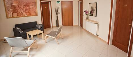 A hotel lobby with a sofa, chairs, a table, a large framed picture, and a mirror.