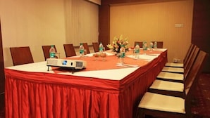 Una sala de conferencias con una larga mesa, sillas, un proyector y botellas de agua.