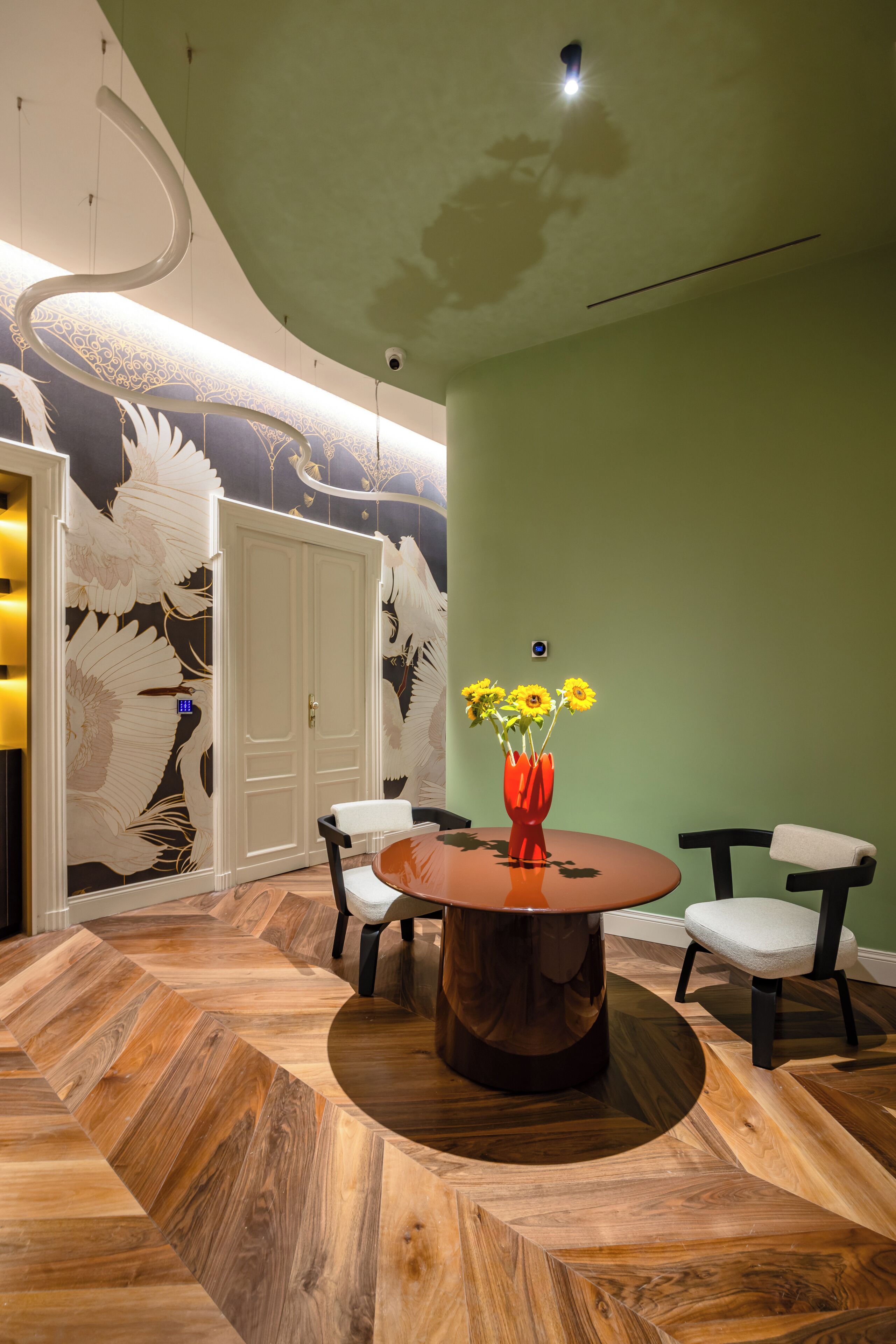 A dining area with a round table, chairs, and a wall with a bird mural.