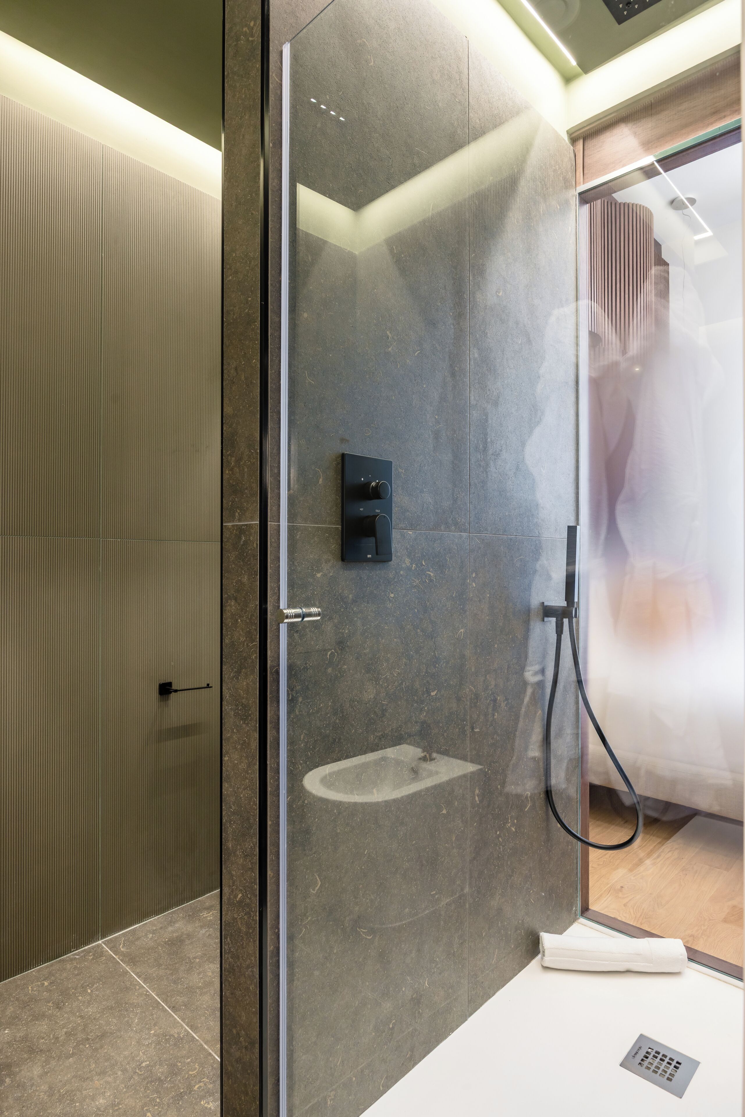 Un baño moderno con ducha de vidrio, lavamanos empotrado y un perchero para toallas.