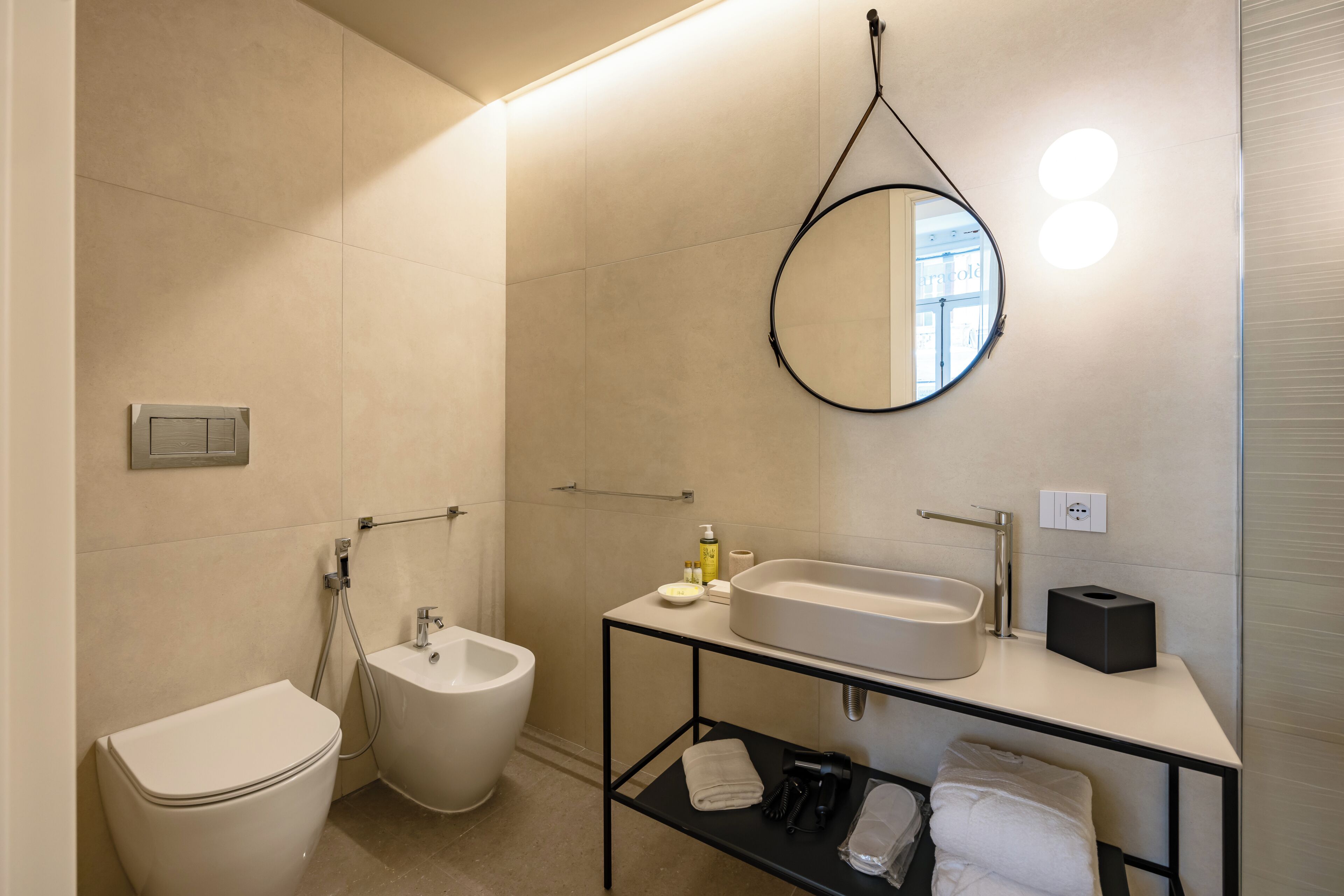 Un baño moderno con inodoro, lavamanos, espejo y bidé.