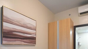 A bedroom with a bed, a wardrobe, and a shower area. - Kuya Awens Staycation Unit 15K (Parañaque)
