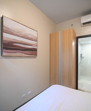 Quarto com cama, guarda-roupa e chuveiro.