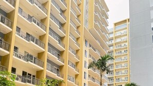 A multi-story residential building with balconies, a swimming pool, and lounge chairs. - Kuya Awens Staycation Unit 15K (Parañaque)
