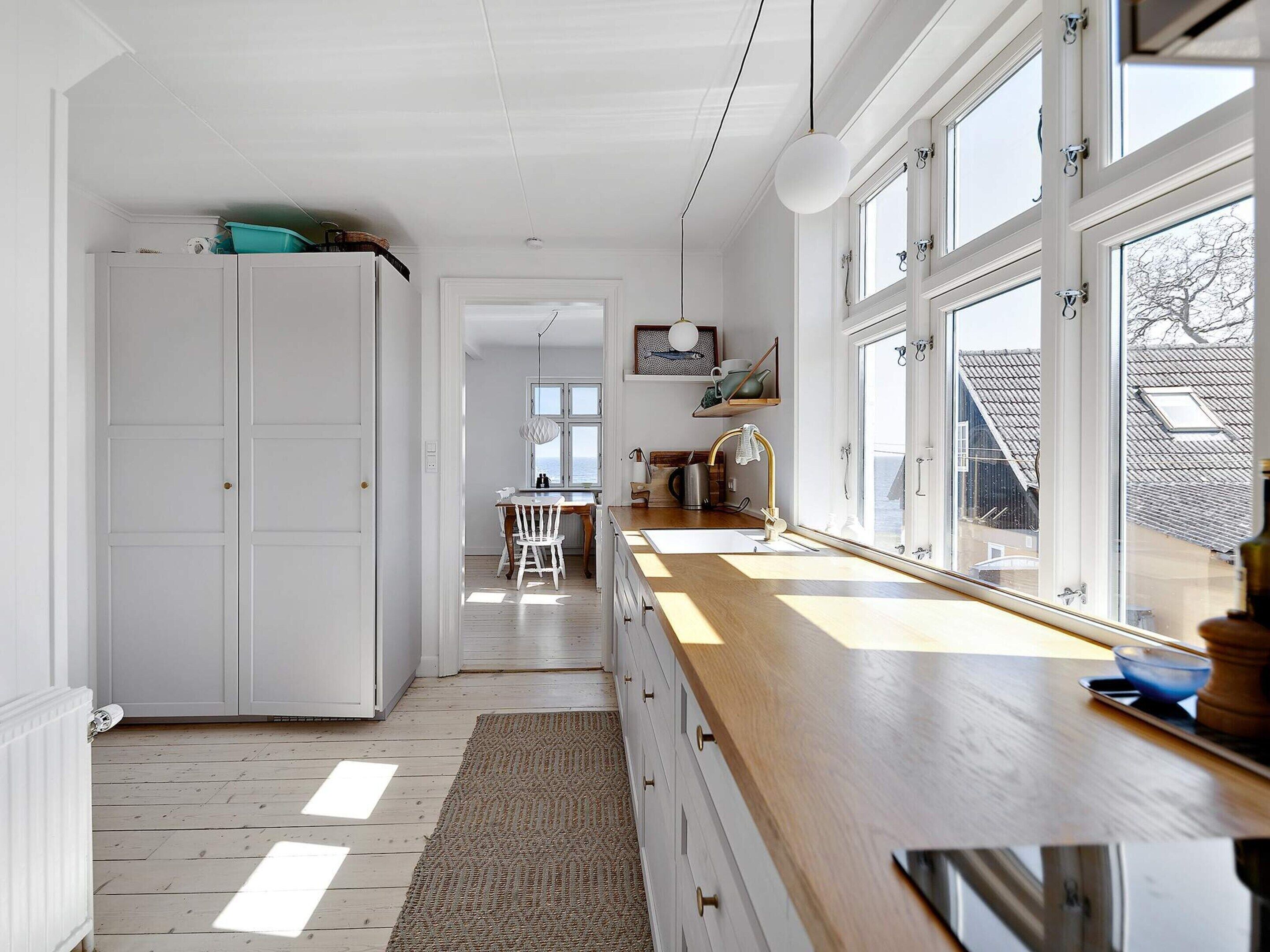 A kitchen with a wooden countertop, a sink, and a window with a view of the outside.