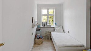 A narrow room with a single bed, a small table, a chair, and a window with a view of greenery. - 5 Star Holiday Home in Svaneke (Svaneke)