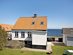 Ein Küstenhaus mit einem Ziegeldach, weißen Wänden und einem kleinen Garten.