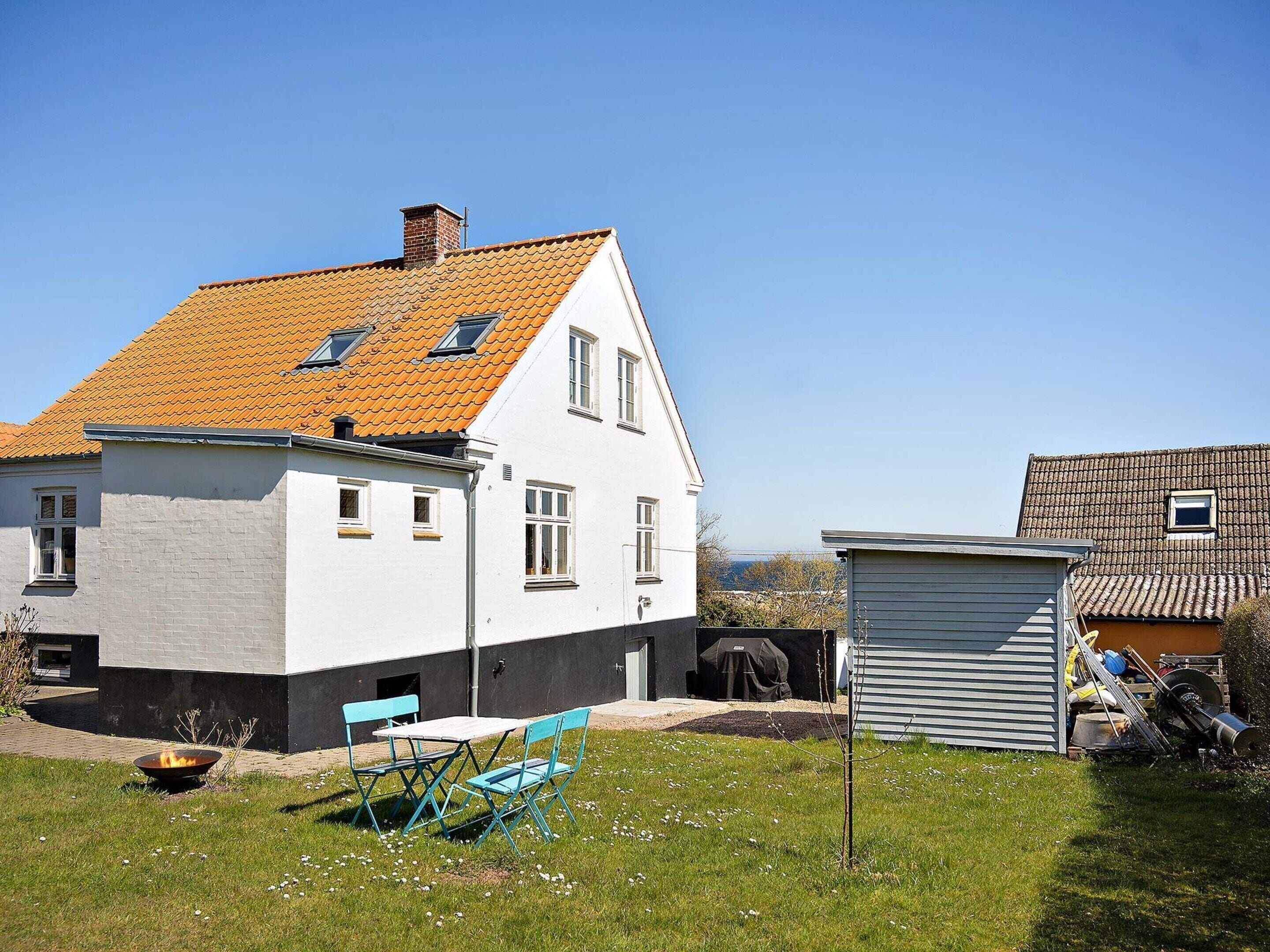 A house with a sloped roof, a small attached garage, and a grassy yard with outdoor furniture.