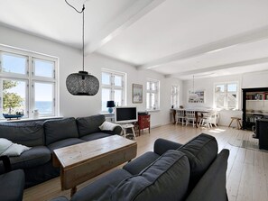 Ein geräumiges Wohnzimmer mit einer großen Couch, einem Holztisch und einem Essbereich mit Tisch und Stühlen.
