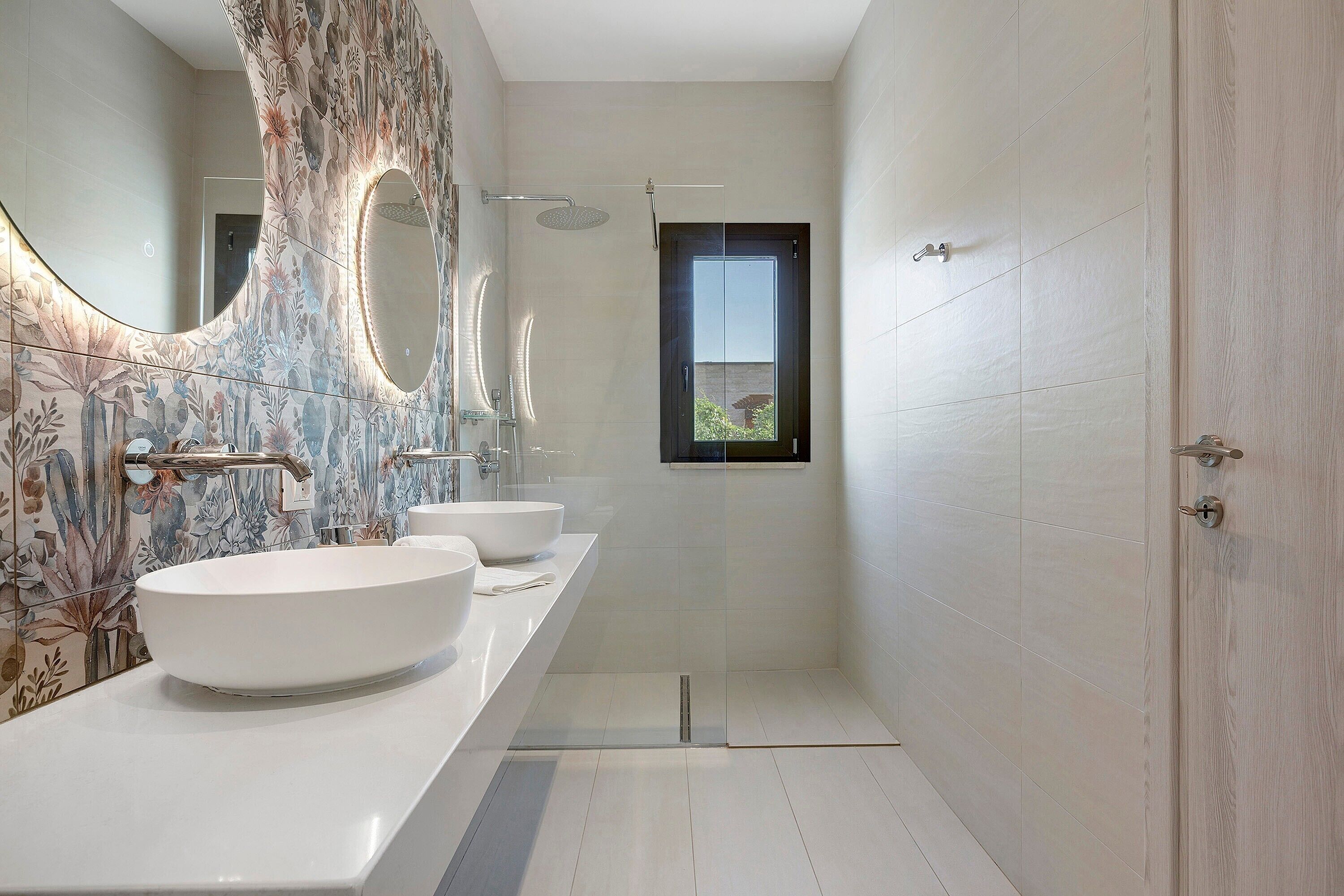 Un bagno moderno con tre lavandini, una doccia e un grande specchio.