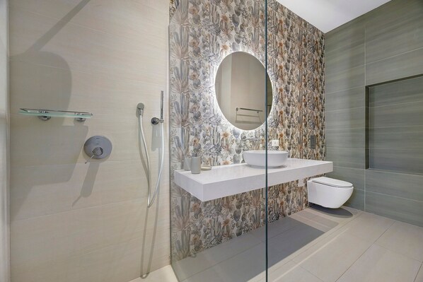 Une salle de bain moderne avec une douche, un lavabo entouré de parois en verre et des toilettes.