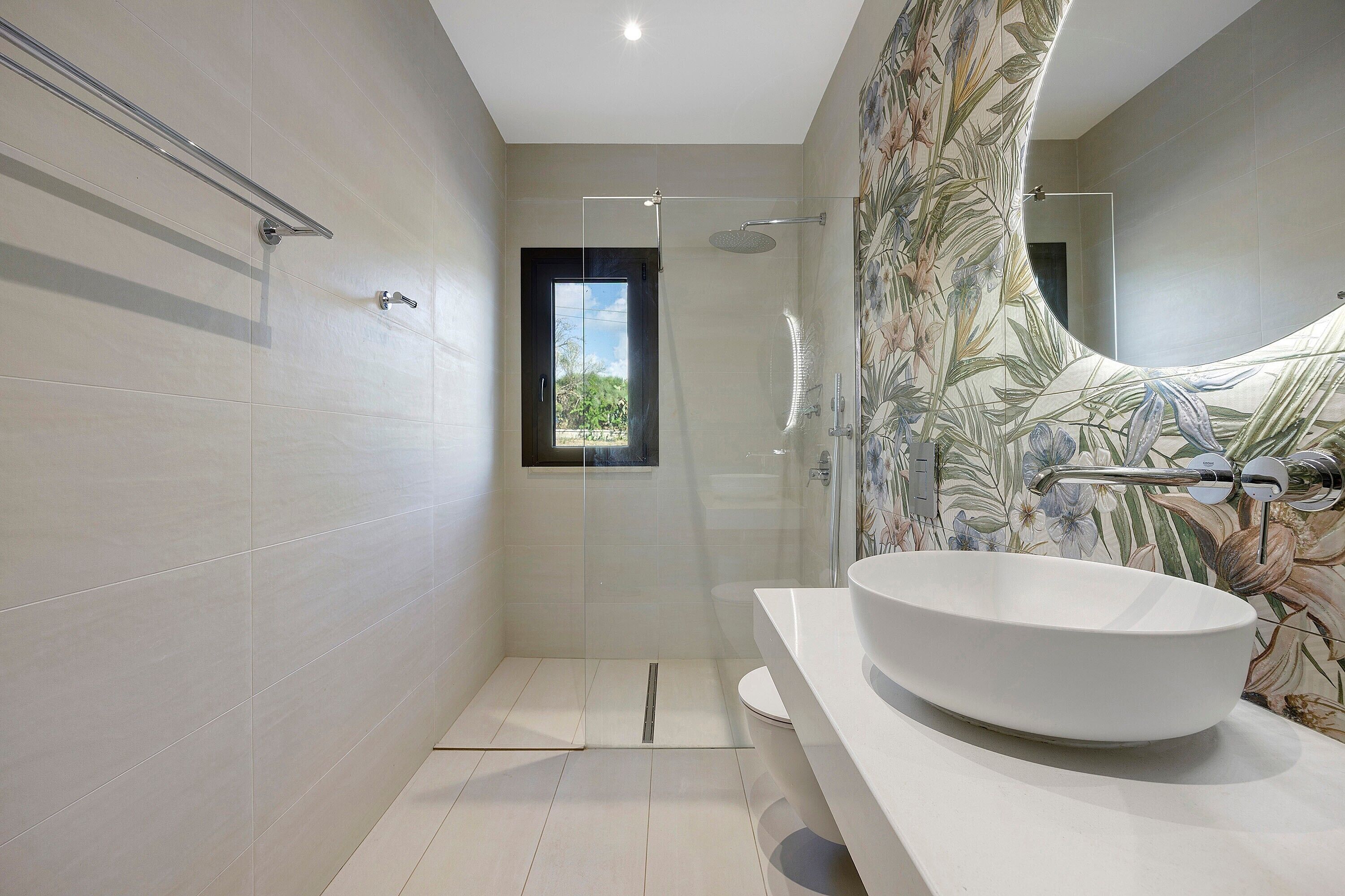 Un bagno moderno con un ampio lavandino bianco, cabina doccia e finestra vista.
