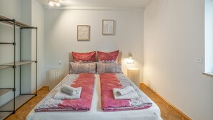 Una camera da letto con un letto, due luci a parete, un termosifone e una scaffalatura.