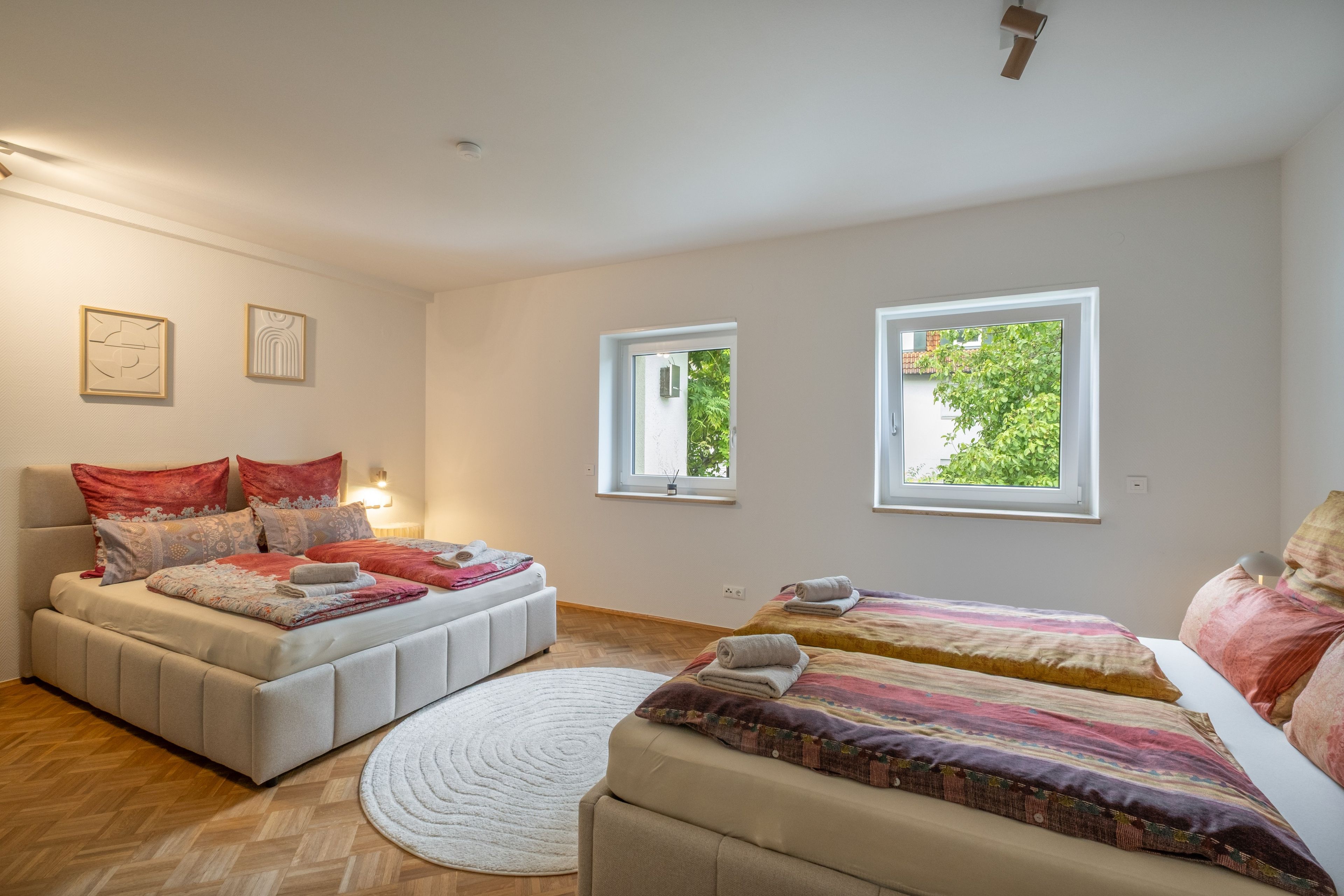 Ein Schlafzimmer mit zwei Betten, einem großen Fenster und einem kleinen Fenster.