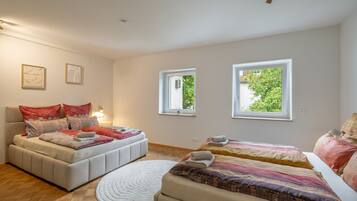 Ein Schlafzimmer mit zwei Betten, einem großen Fenster und einem kleinen Fenster.