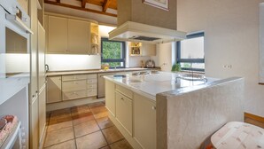 Una cucina con isola centrale, mobili bianchi e una finestra che offre luce naturale.