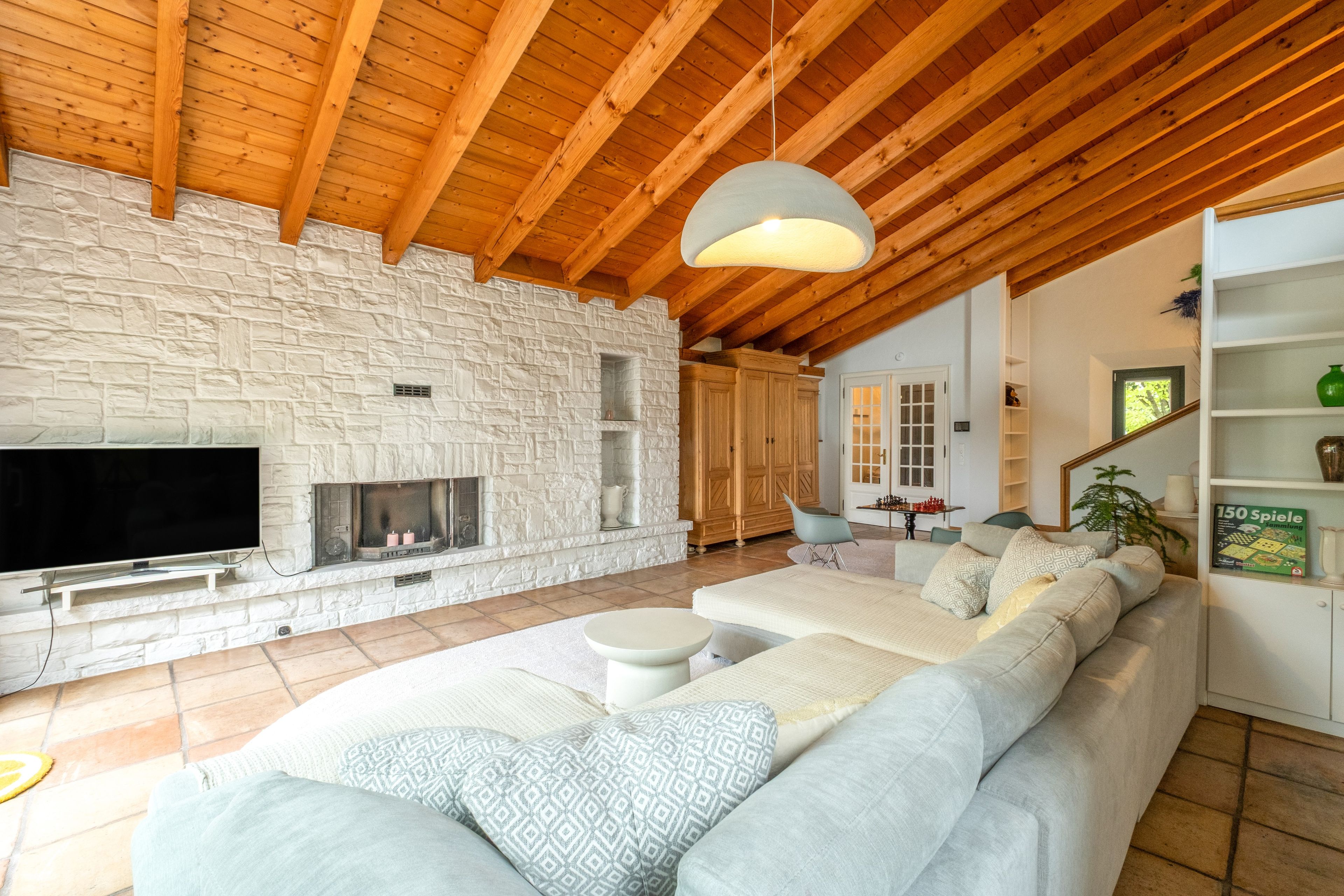 Ein Wohnzimmer mit Kamin aus Stein, einer großen Couch und einem Fernseher.