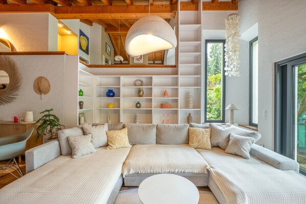 A modern living room with a sectional sofa, a white coffee table, and a hanging light fixture.