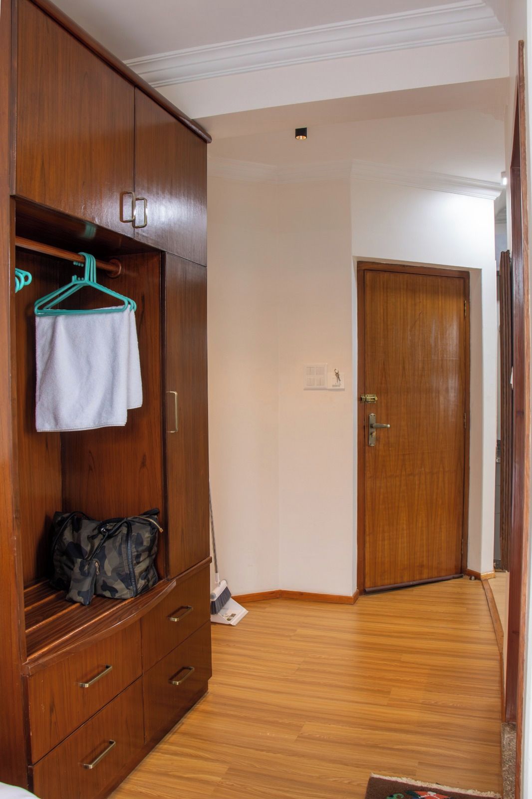 Ein Flur mit einem Holzschrank, einem aufgehängten Handtuch und einer Tür am Ende.