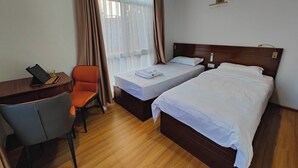 A hotel room with two beds, a desk with a chair, and a window with curtains. - Clean 1-bedroom studio apartment with AC private kitchen bathroom at Swayambhu (Kathmandu)