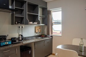 A modern kitchen with grey cabinets, a stainless steel range hood, and a window with curtains.