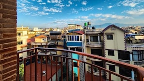 A residential area with multiple buildings, a clear sky, and a balcony with a metal railing. - Clean 1-bedroom studio apartment with AC private kitchen bathroom at Swayambhu (Kathmandu)