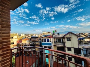 Ein Wohngebiet mit mehreren Gebäuden, blauem Himmel und einem Balkon mit Metallgeländer.