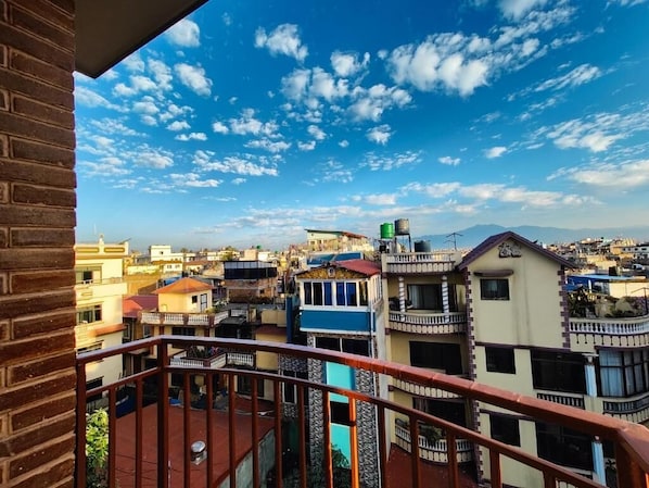 A residential area with multiple buildings, a clear sky, and a balcony with a metal railing.