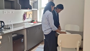 A modern kitchen with grey cabinets, a stainless steel range hood, and a window with curtains. - Clean 1-bedroom studio apartment with AC private kitchen bathroom at Swayambhu (Kathmandu)