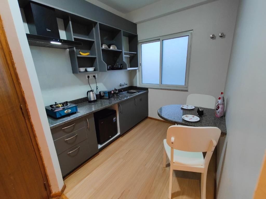 A compact kitchen with grey cabinets, a built-in stove, a sink, and a window.