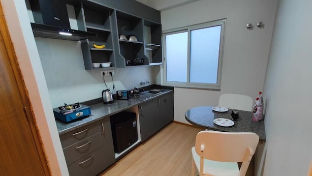 A compact kitchen with grey cabinets, a built-in stove, a sink, and a window. - Clean 1-bedroom studio apartment with AC private kitchen bathroom at Swayambhu (Kathmandu)