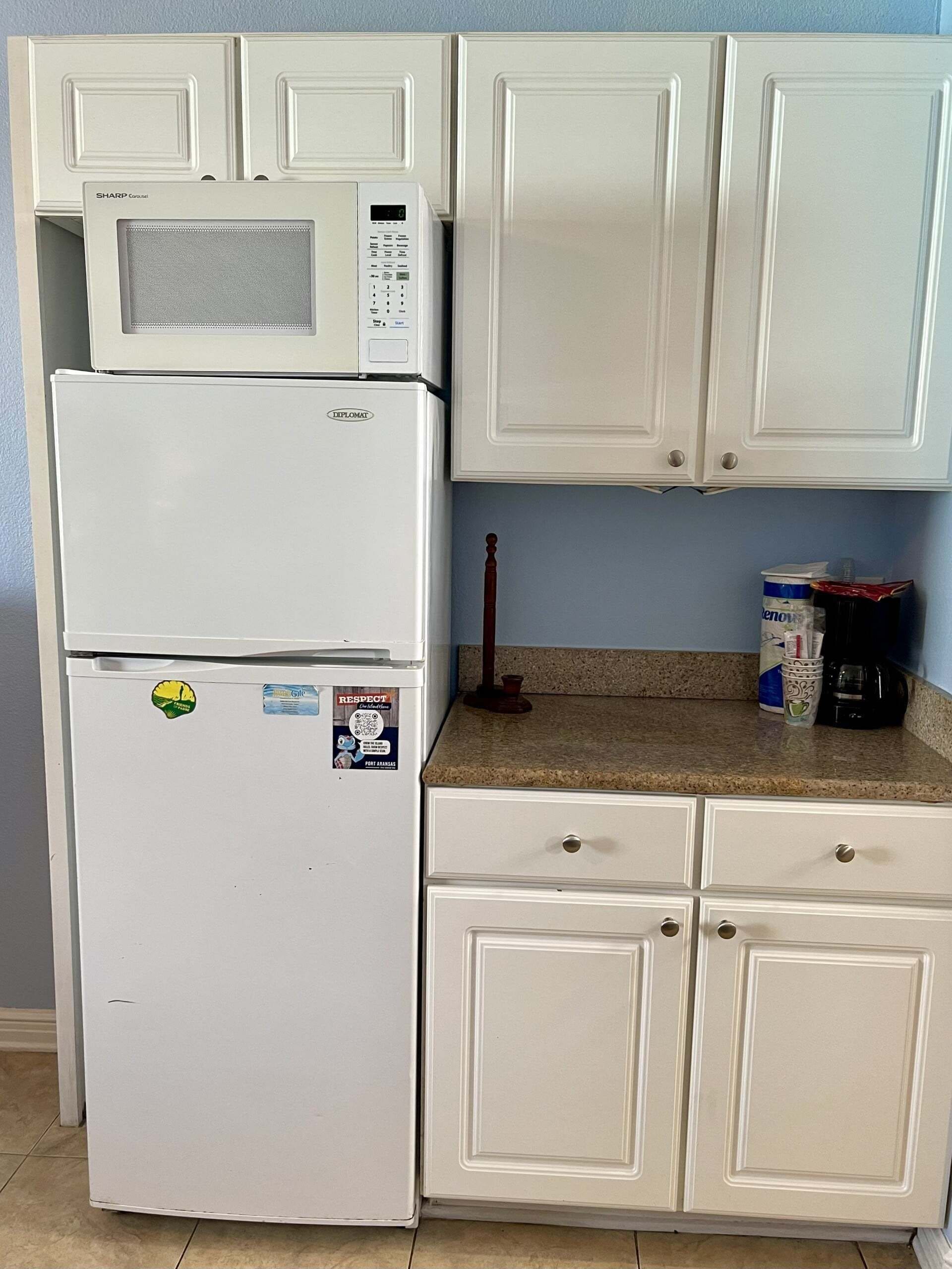 A kitchen with a microwave, a refrigerator, and cabinets.