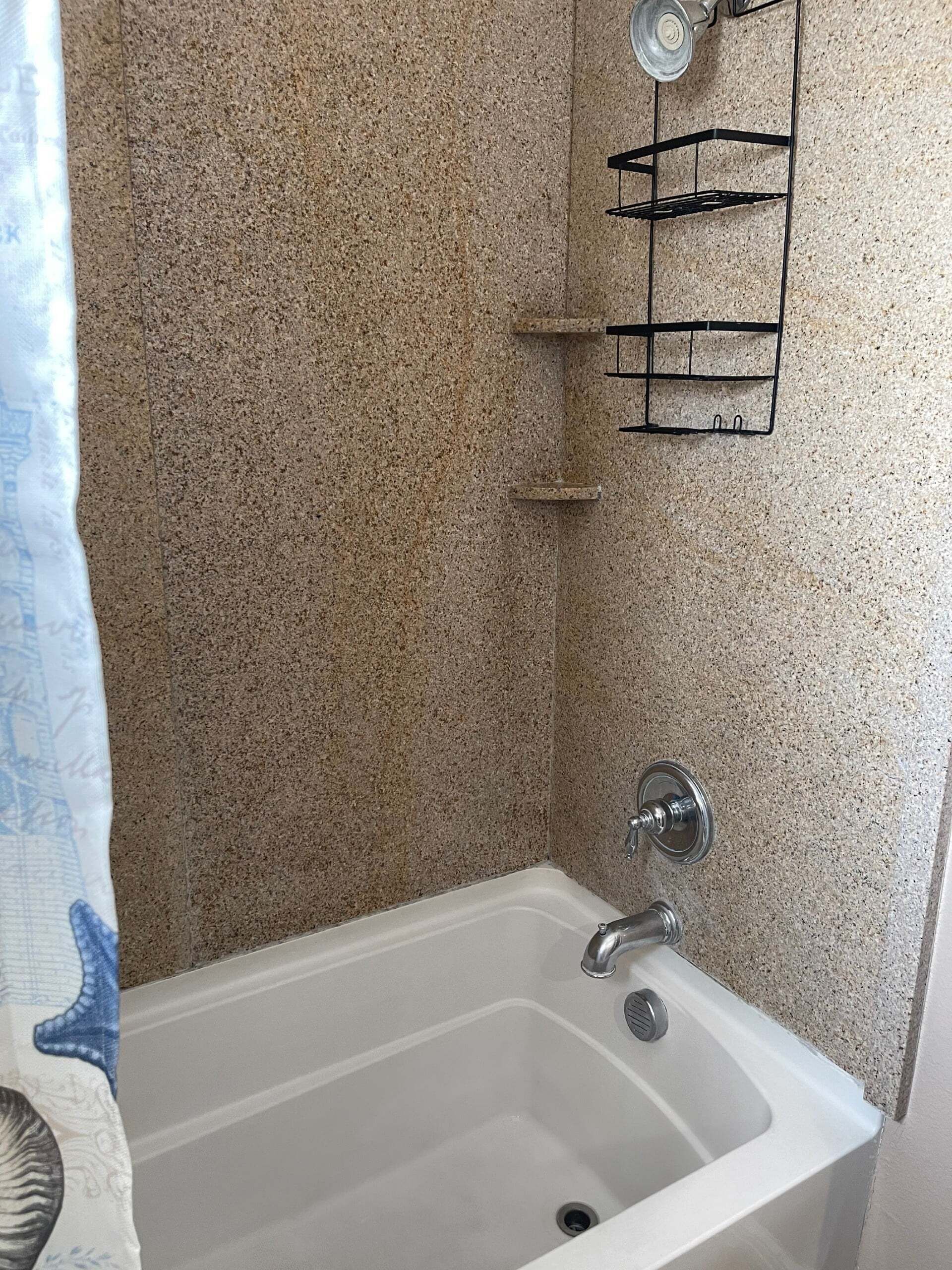 A bathroom with a white bathtub, a towel rack, and a shower head.