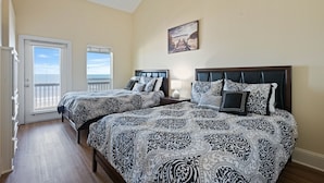 A bedroom with two beds, a ceiling fan, a painting, and a view through a door. - Kiki Beach 4 Bedroom Home (Port Bolivar)