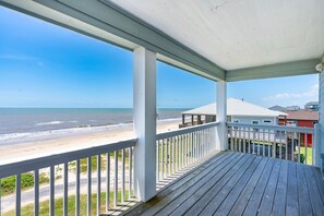 Eine Holzterrasse mit Blick auf den Strand und den Ozean.