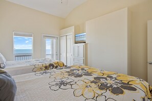 Ein Schlafzimmer mit einem Bett, einem Fernseher auf einem Tisch und Meerblick durch ein Fenster.