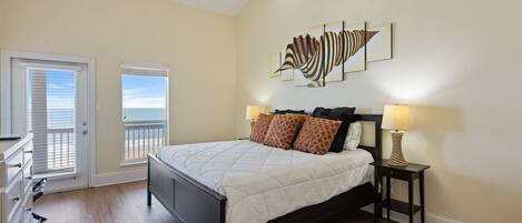 A bedroom with a bed, two bedside lamps, a ceiling fan, and artwork on the wall.