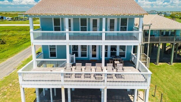 A two-story building with a balcony and outdoor seating area. - Kiki Beach 4 Bedroom Home (Port Bolivar)