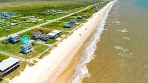 An aerial view of a coastal area with a beach, houses, and a pier. - Kiki Beach 4 Bedroom Home (Port Bolivar)