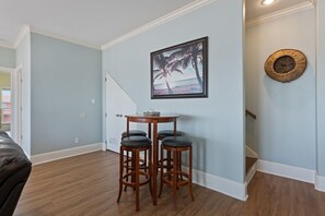Ein Zimmer mit einer hellblauen Wand, Holzboden, einem gerahmten Bild von Palmen und einer runden, strukturierten Wanddekoration.
