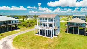 A coastal property with a two-story house featuring a balcony, a covered porch, and a view of the ocean. - Kiki Beach 4 Bedroom Home (Port Bolivar)