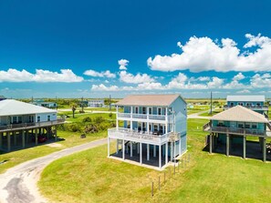 A coastal property with a two-story house featuring a balcony, a covered porch, and a view of the ocean. - Kiki Beach 4 Bedroom Home (Port Bolivar)