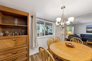 A dining area with a wooden table and chairs, a chandelier, and a view of the outdoors through a window. - 1168hc 3 Bedroom Condo (South Lake Tahoe)