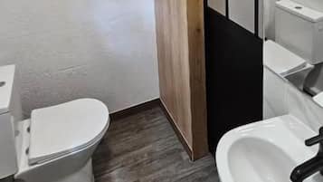 A compact bathroom with a toilet, sink, and wooden paneling.