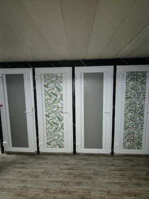 Four doors with frosted glass panels, a wooden floor, and a black wall.
