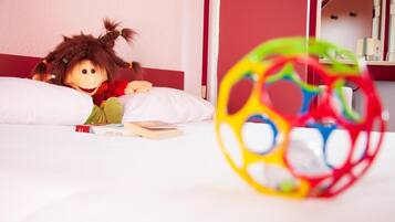 Quarto com uma cama, uma boneca e um brinquedo de bola colorido.
