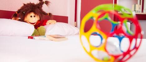 A room with a bed, a doll, and a colorful ball toy.