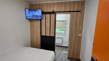 A hotel room with a bed, a television mounted on the wall, and a sliding door leading to a bathroom.