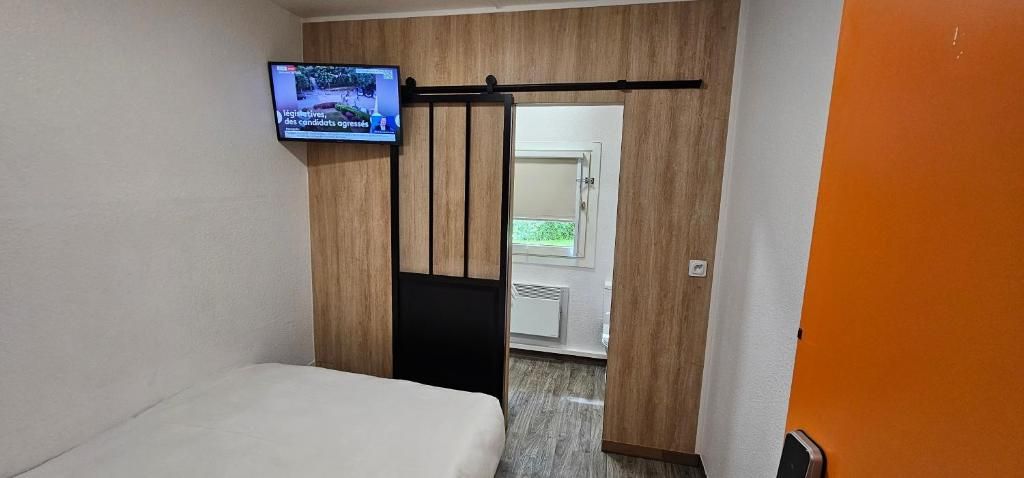 Een hotelkamer met een bed, een aan de muur bevestigde televisie en een schuifdeur naar een badkamer.